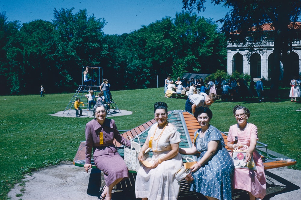 a group of women sitting on top of a park bench