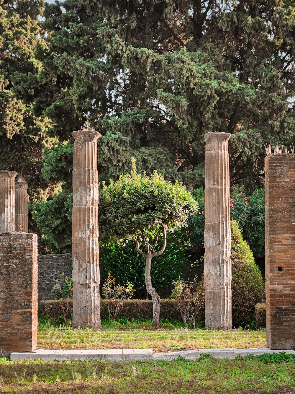 a group of stone pillars sitting next to a lush green park