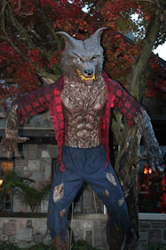 A shadowy figure of a werewolf silhouetted against a full moon over a quiet New England town.