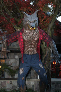 A shadowy figure of a werewolf silhouetted against a full moon over a quiet New England town.