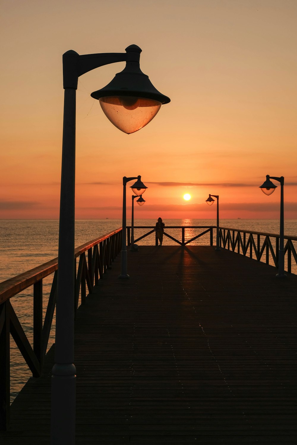 a person standing on a pier at sunset