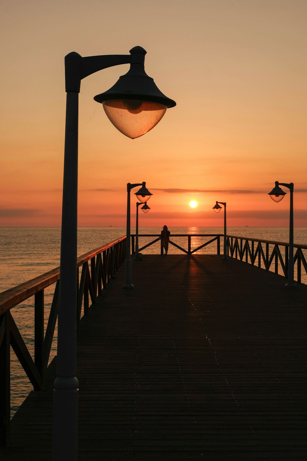 una persona parada en un muelle al atardecer