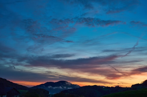 A vibrant landscape photograph showcasing a sunset over rolling hills.