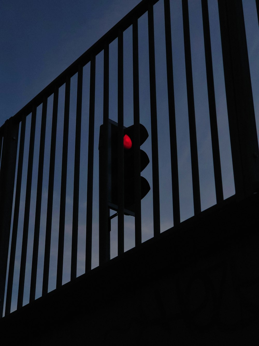 a traffic light on a metal fence with a blue sky in the background