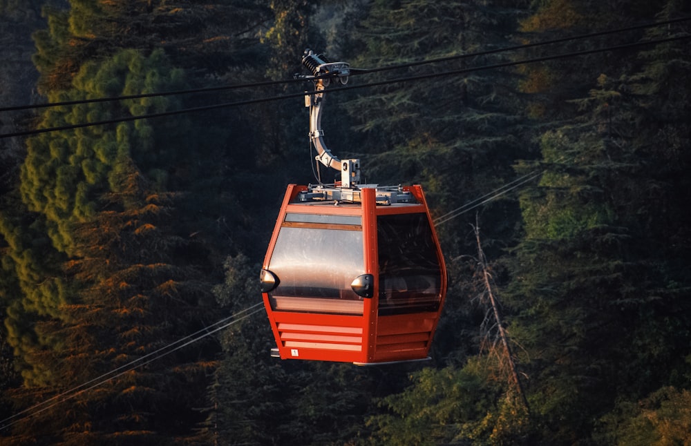 a red cable car in the middle of a forest