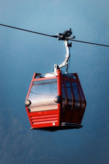 a red cable car with a sky background