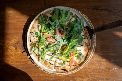 A vibrant pizza topped with fresh vegetables and melted cheese on a rustic wooden table.
