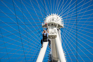 Worker in climbing gear painting a tall steel structure on a sunny day