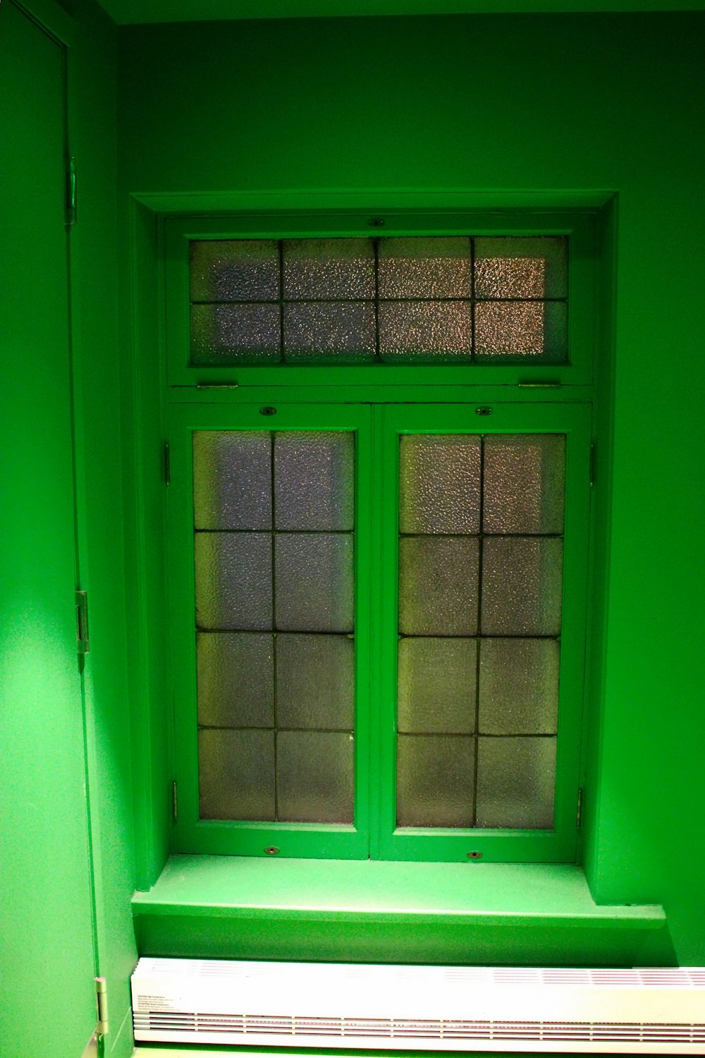 una habitación verde con una ventana y un radiador
