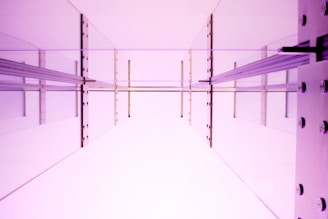 An abstract architectural space with reflective surfaces, characterized by geometric lines and angles. The perspective suggests an upward view through a transparent or mirrored structure, creating a sense of depth and openness.