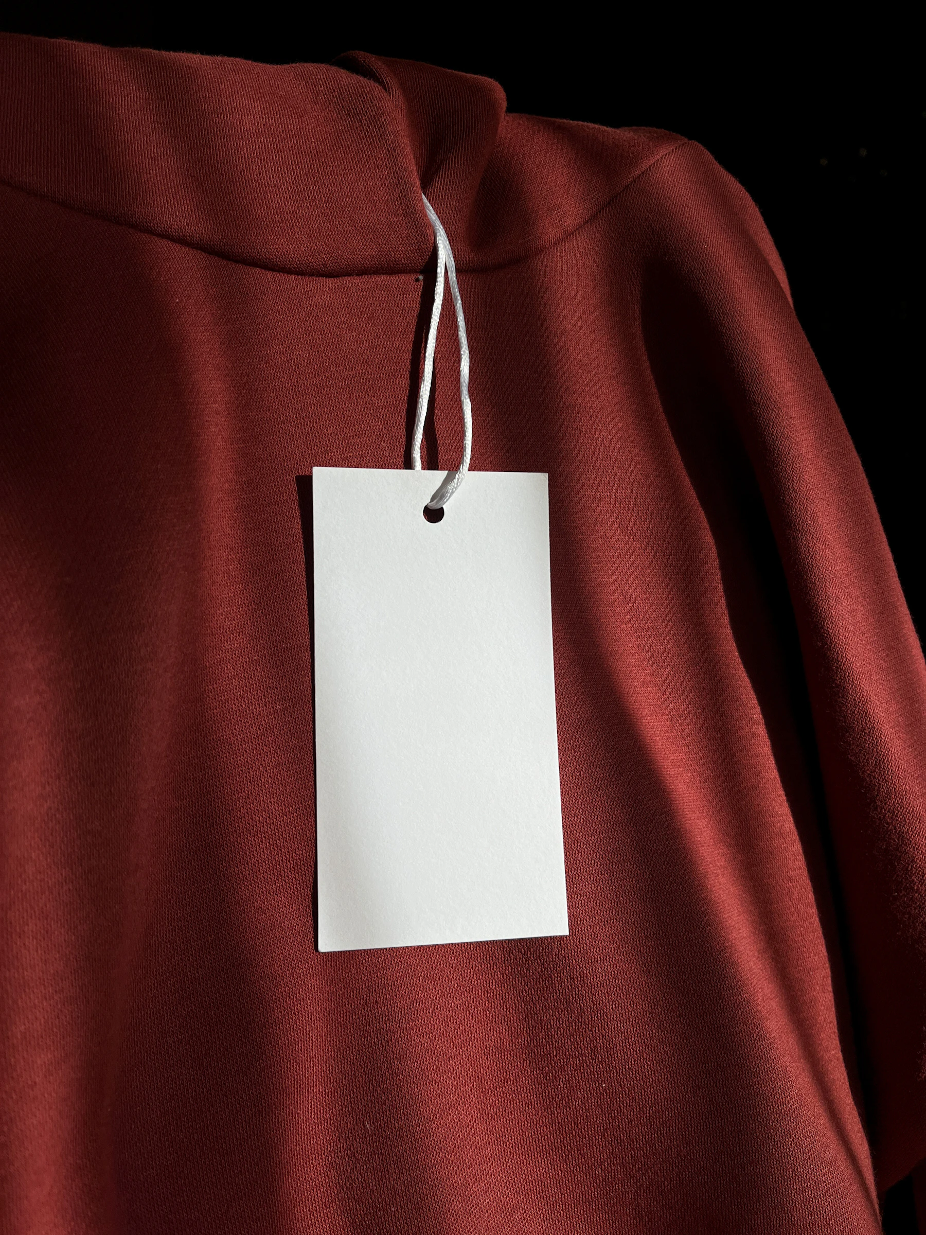 a red sweatshirt with a white tag attached to it