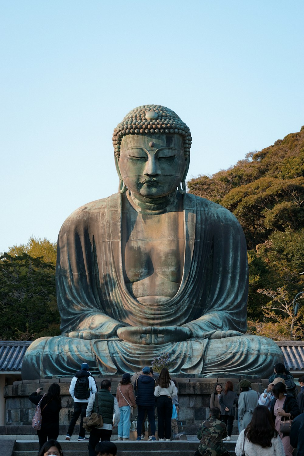 a group of people standing around a large buddha statue