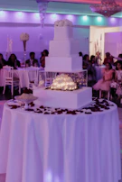 Close-up of the illuminated wedding cake under vibrant party lights.