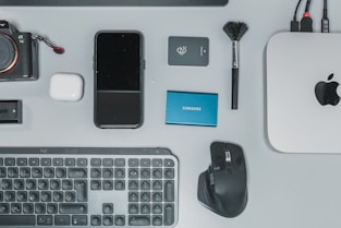 a desk with a keyboard, mouse, cell phone and other items
