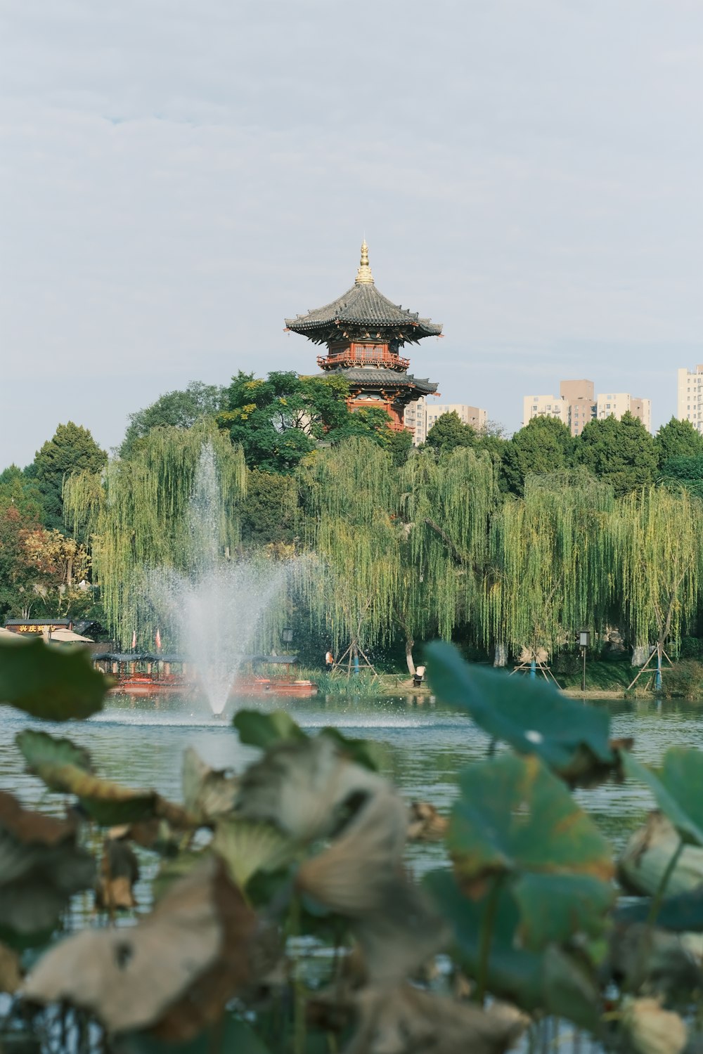 a pond with a fountain and a pagoda in the background