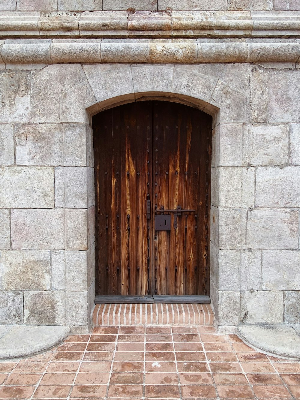 un bâtiment en pierre avec deux portes en bois et une passerelle en brique