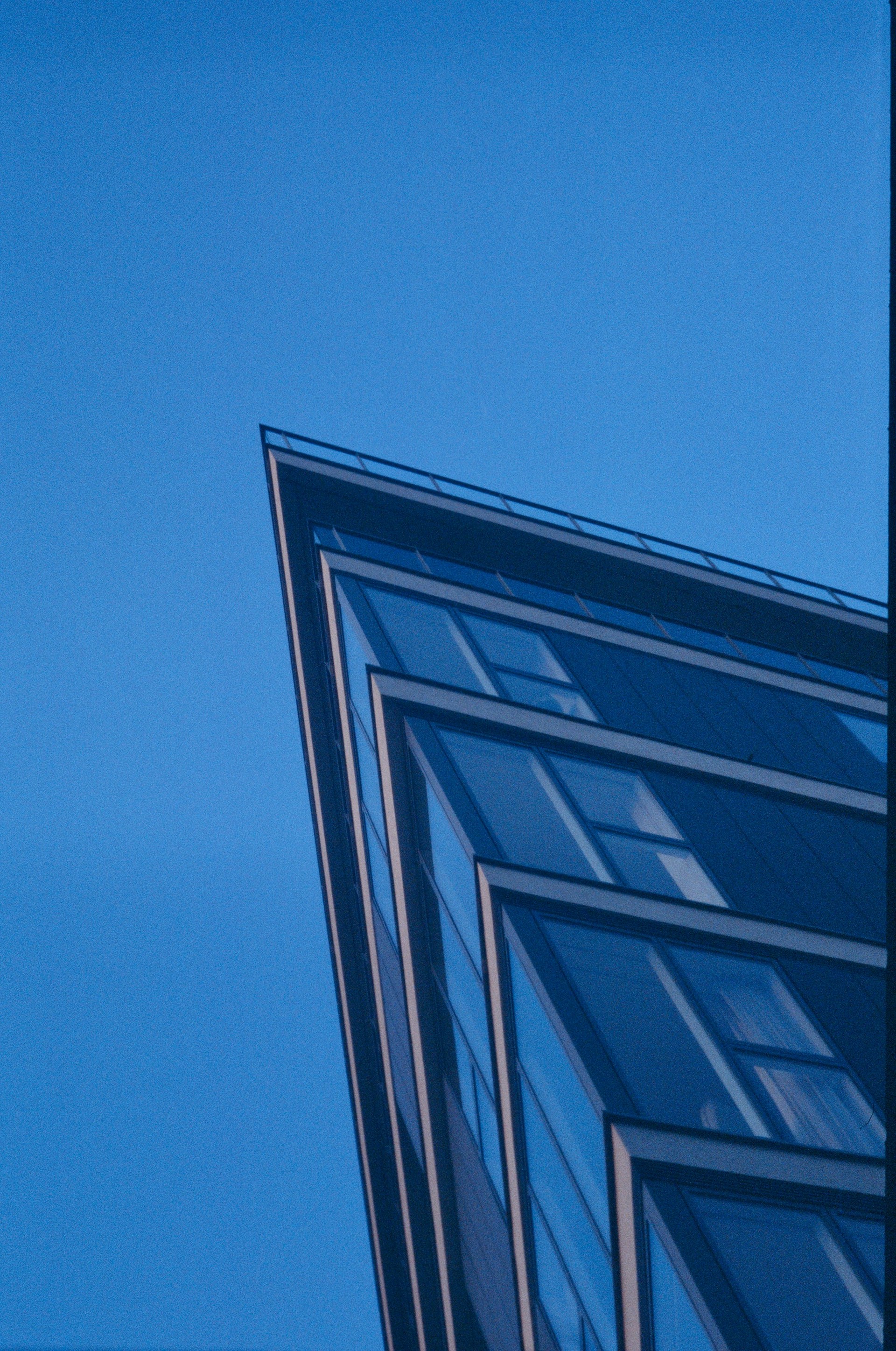 An exterior shot of a modern architectural tower with sharp angles against a clear sky.