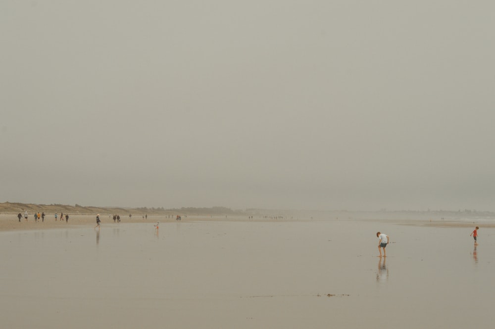 a group of people standing on top of a sandy beach