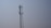 A tall metal telecommunications tower stands against a clear blue sky. The tower features multiple antennas attached along its sides, indicating its use for communication purposes.