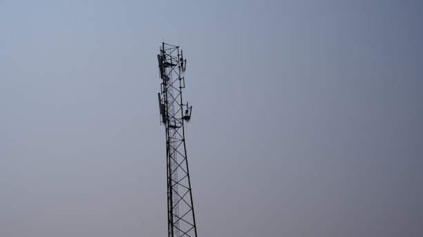 A modern telecommunications tower against a clear blue sky.