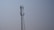 A tall metal telecommunications tower stands against a clear blue sky. The tower features multiple antennas attached along its sides, indicating its use for communication purposes.