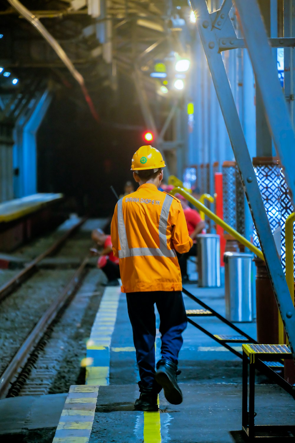 a man in a yellow jacket is walking down a train track