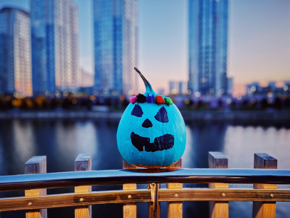 a blue pumpkin sitting on top of a wooden fence
