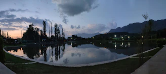 A peaceful mountain lake reflecting the cloudy sky at dusk with subtle light.