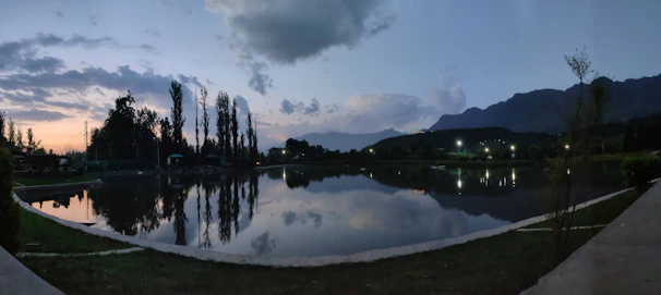 A peaceful mountain lake reflecting the cloudy sky at dusk with subtle light.