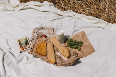 A picnic blanket spread on green grass with colorful snacks and a storybook.