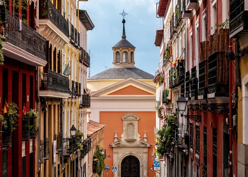 a narrow city street with a church steeple in the background