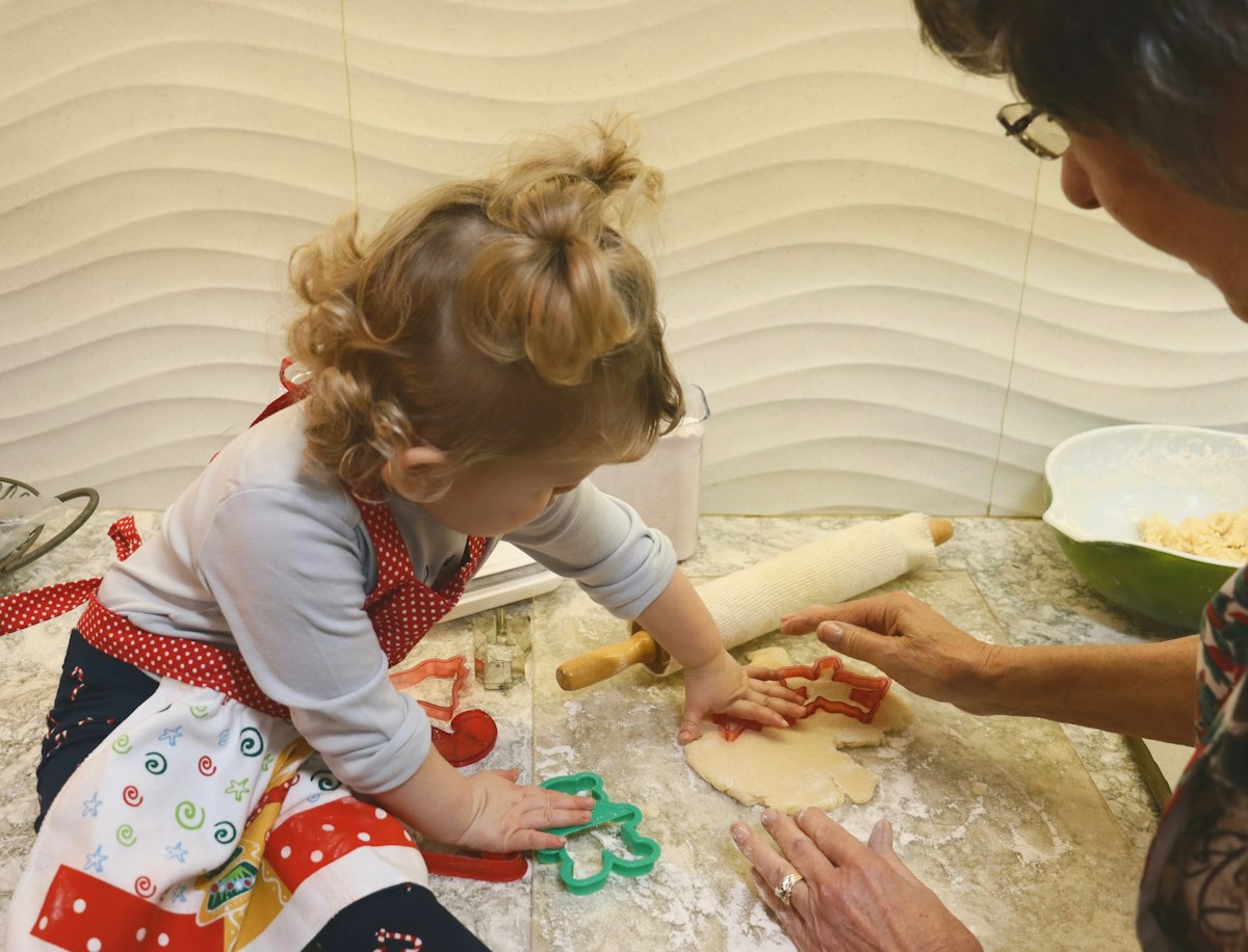 A mom and little girl making dough together at a table