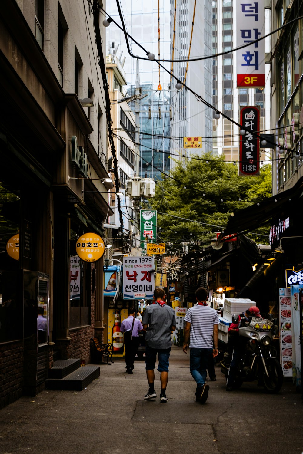 a group of people walking down a street next to tall buildings