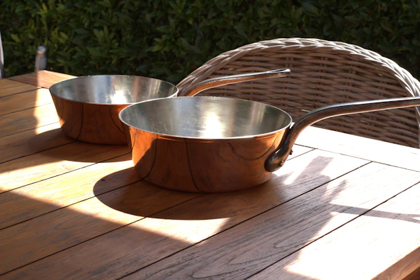 Artisan copper cookware gleaming on a rustic wooden table.