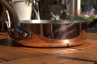 A shiny aluminum saucepan with a wooden handle on a rustic kitchen counter