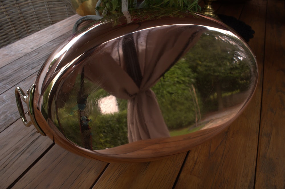 a mirror on a wooden table reflecting a tree