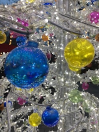 A close-up of colorful, sparkling Christmas ornaments made from natural materials hanging on a festive tree.