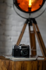 A vintage-style camera resting on a wooden table with film reels and a soft warm light.