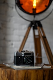 A vintage camera on a wooden table surrounded by old photographs.