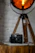 A softly lit vintage camera on a wooden table surrounded by film rolls and torn magazine pages.