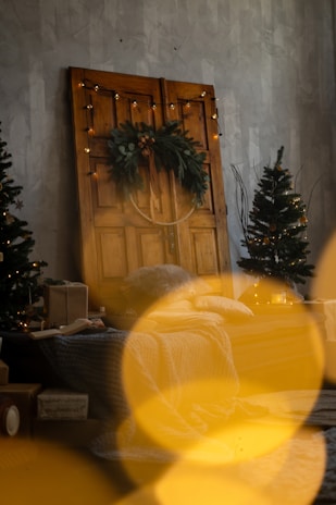 Cozy Christmas wreath hanging on a rustic wooden door with soft fairy lights.