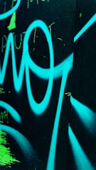 Alien graffiti sprayed across a muted silver wall with neon highlights.