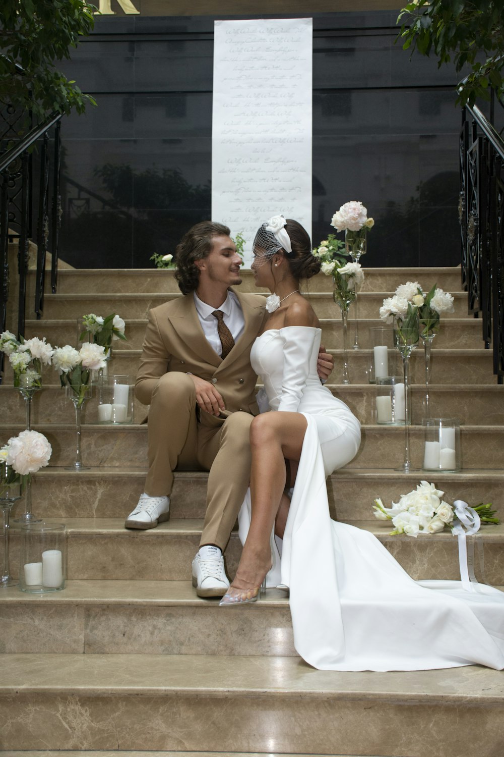 a bride and groom sitting on the steps of a building