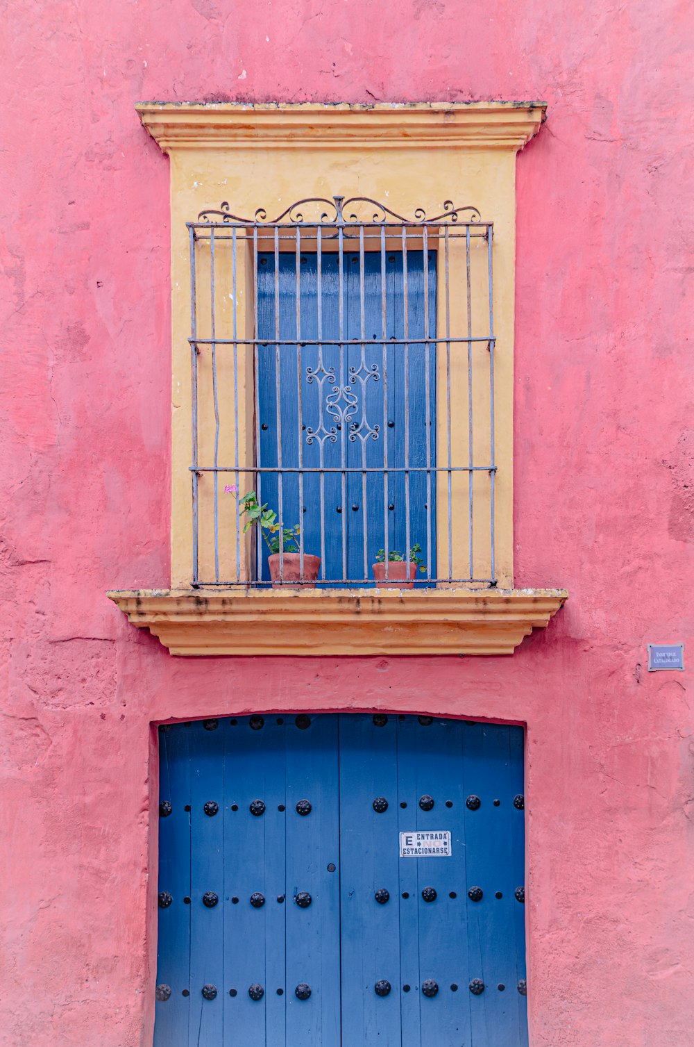 ein rosafarbenes Gebäude mit einer blauen Tür und einem Fenster