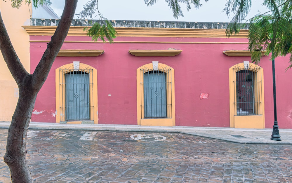 a pink and yellow building with a tree in front of it