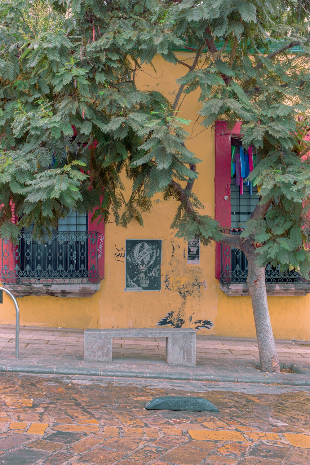 a bench in front of a yellow building with red shutters