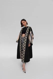 Model walking confidently in a futuristic, tailored black coat with clean lines