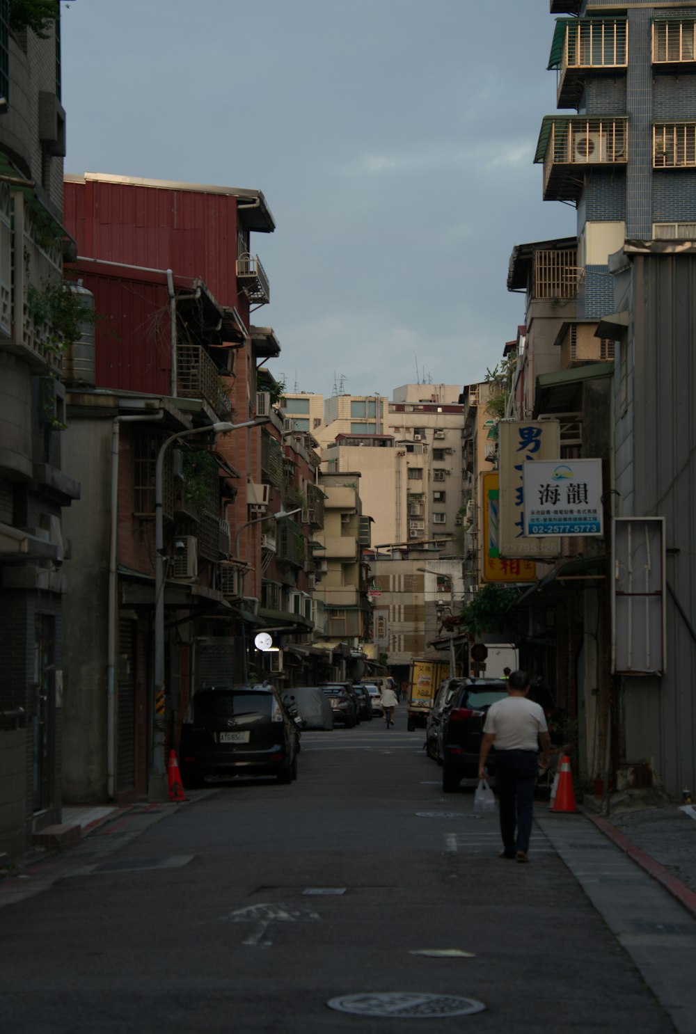 a man walking down a street next to tall buildings