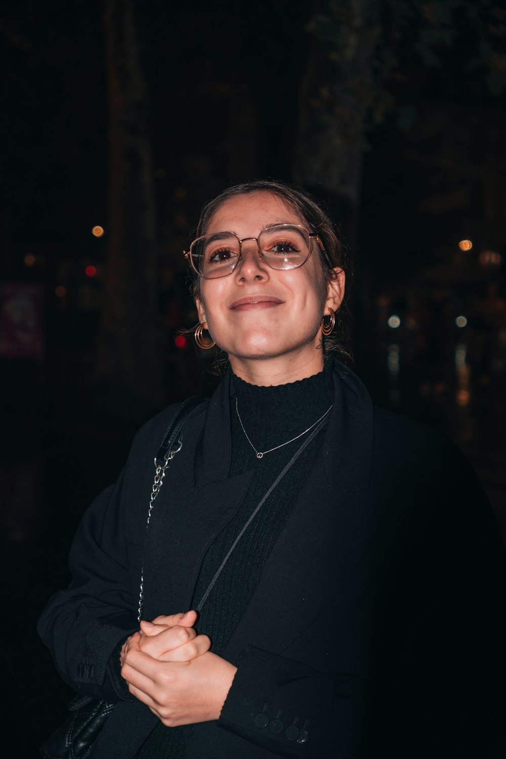 a woman wearing glasses standing in the dark