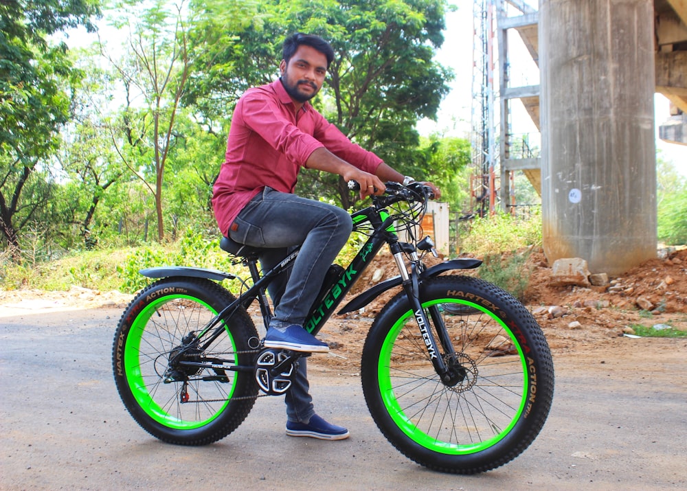 a man sitting on a black and green bike